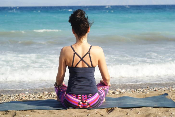 A woman looks at the sea in a lotus position