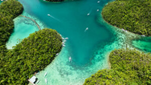 Clear shallow water with coral reef and boats near islands. Siargao, Philippines.