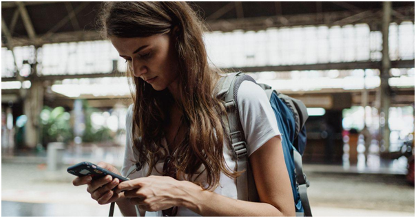 Person focused on their smartphone while wearing a backpack