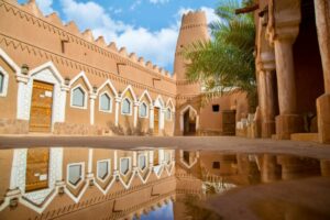 Traditional mud-brick architecture reflected in a puddle at the Ushaiqer Heritage Village in the Najd region of central Saudi Arabia