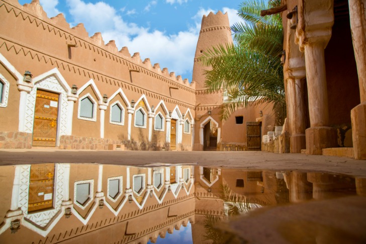 Traditional mud-brick architecture reflected in a puddle at the Ushaiqer Heritage Village in the Najd region of central Saudi Arabia