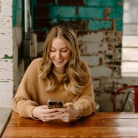 a woman sitting at a table looking at her cell phone