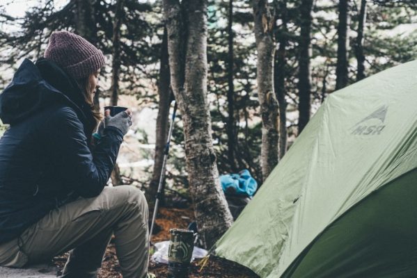 A girl by a tent drinking tea