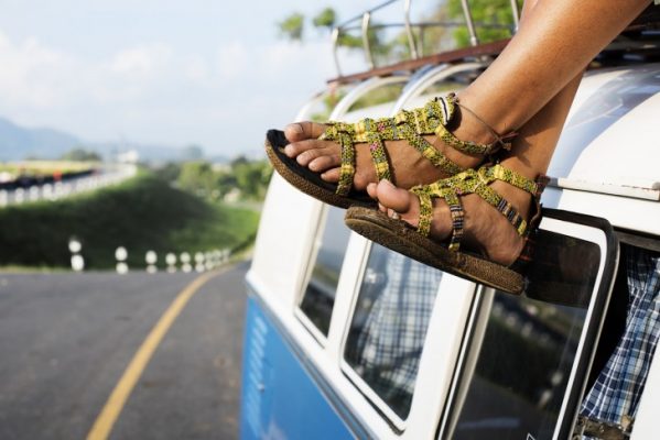 Girl sitting on the car roof wearing sandals