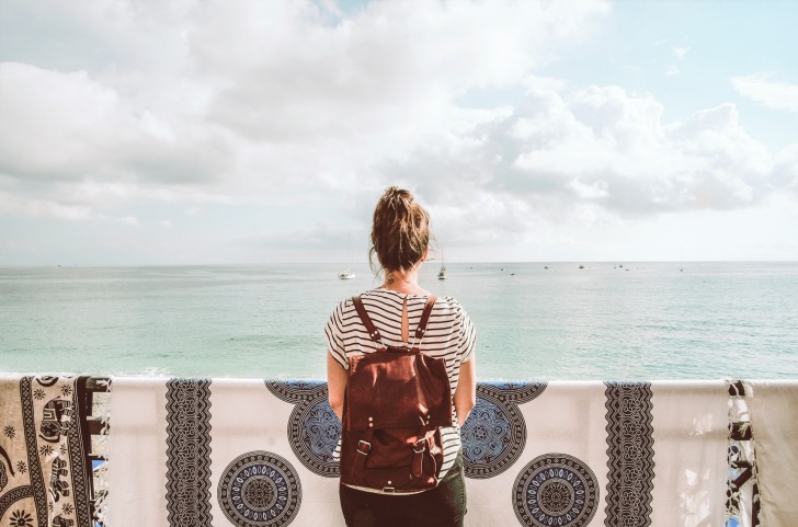 woman standing on the balcony through her travels