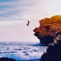 Man jumping from the rock into the water