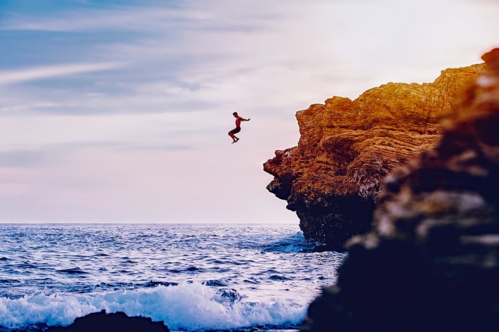 Man jumping from the rock into the water