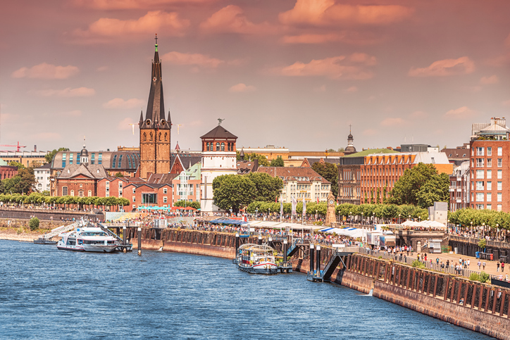 Recognizable architectural towers of the city of Dusseldorf and transportation waterway of the whole of Germany - Rhine River, along which large barges and small ships and boats scurry.