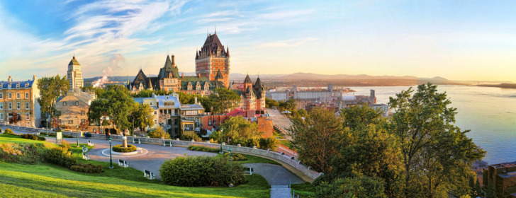 Panoramic view of Chateau Frontenac surrounded by greenery in Old Quebec, Canada at sunrise