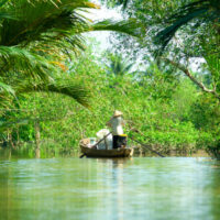 Woman driving a boat in the mekong delta. Vietnam.