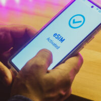 Mobile phone displaying the message eSIM activated. Digital SIM or embedded SIM to allow cellular connection, night time, close up image.