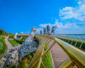 Da Nang Golden Bridge in Ba Na hills, Da Nang, Vietnam on a sunny day. Lifted by two giant concrete hands. Iconic world famous bridge in the mountains with Vietnamese landscape