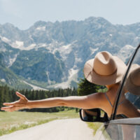 Happy beautiful woman traveling by car in mountains. Travel nature outdoors