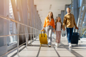 Caucasian family walking together at airport with luggage in bright hall