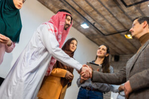 Confident Arab businessman shaking hands with professional colleagues after a successful meeting. Concept of trust, mutual respect, and international business growth