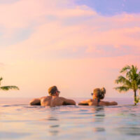 Couple looking at beautiful sunset in infinity pool
