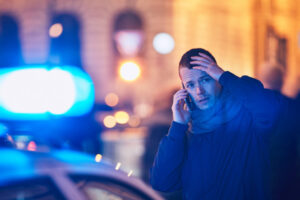 Young man calling after a crisis situation on city street. Themes crime, emergency medical service, fear or help.