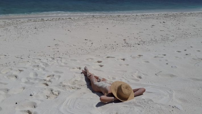 A girl with a hat lying on the beach