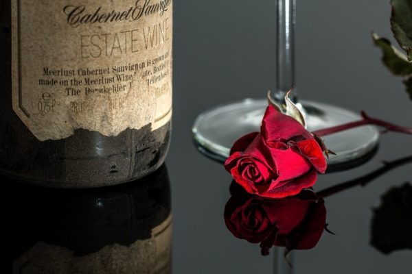 A bottle of wine and a red rose