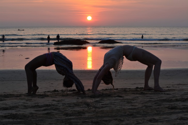 Two people doing yoga on the beach