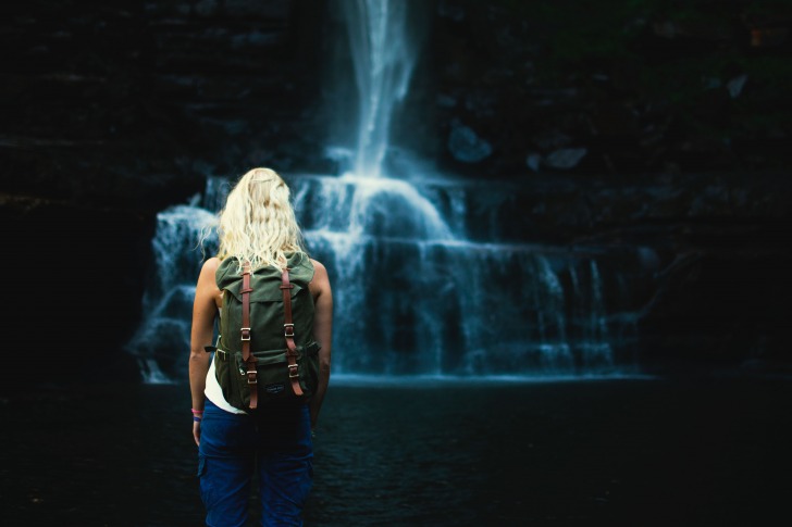 Girl with backpack sees cave waterfall