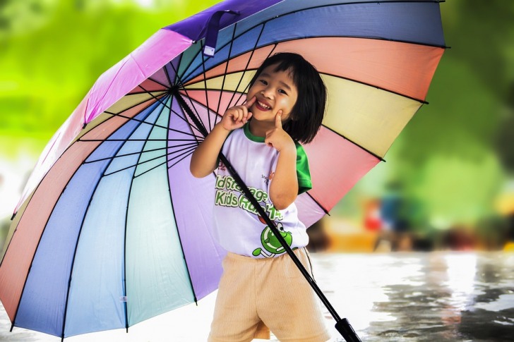 Smiling girl holding a multicolored umbrella