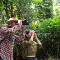 A young man and a young woman climbs a telescope to travel and has a happy smile.