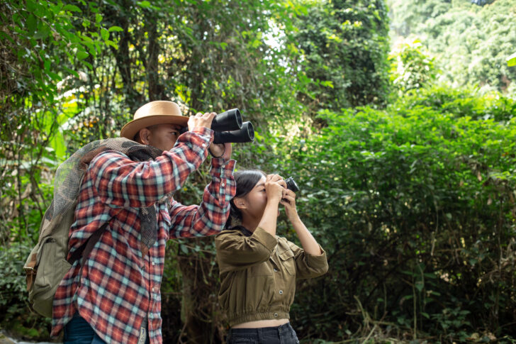 A young man and a young woman climbs a telescope to travel and has a happy smile.